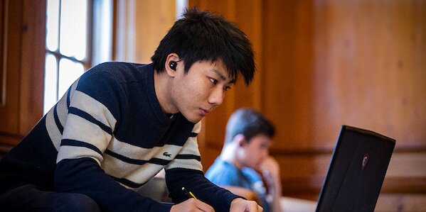 A student in a striped sweater uses a laptop.